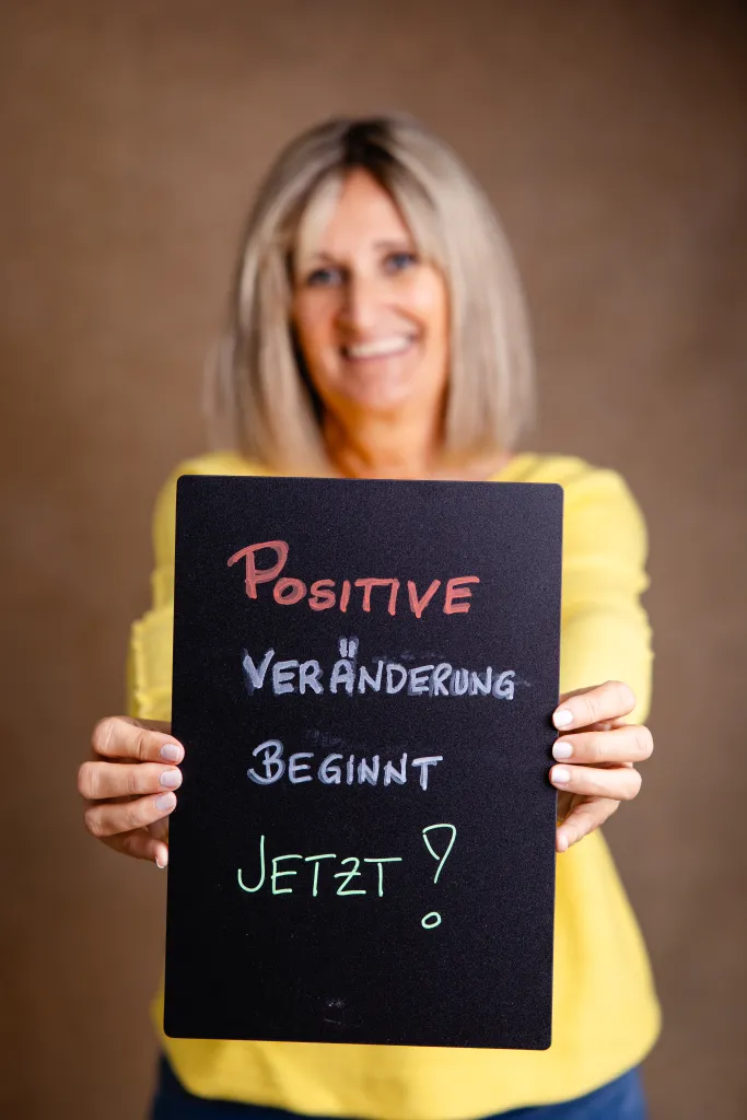 Susanne Eichhorn hält eine Tafel: Positive Veränderung beginnt jetzt!