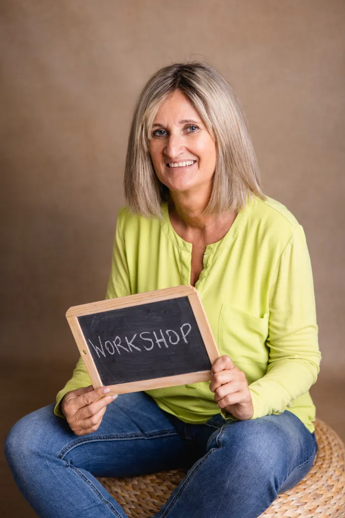 Susanne Eichhorn hält eine Tafel mit der Aufschrift Workshop